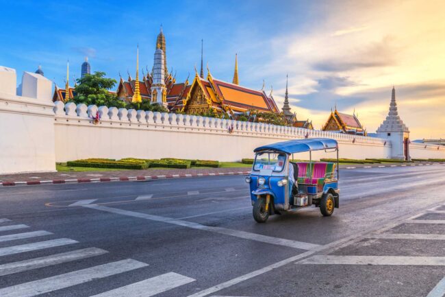 Tuk Tuk is parking in front of Wat Phra Kaeo or Grand Palace, Bangkok, Thailand. This is a beautiful scene of the palace with the twilight sky.
